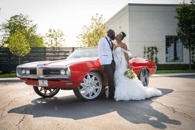 Newlyweds beside a classic red Pontiac after their Indianapolis wedding, by Ken Floyd Media