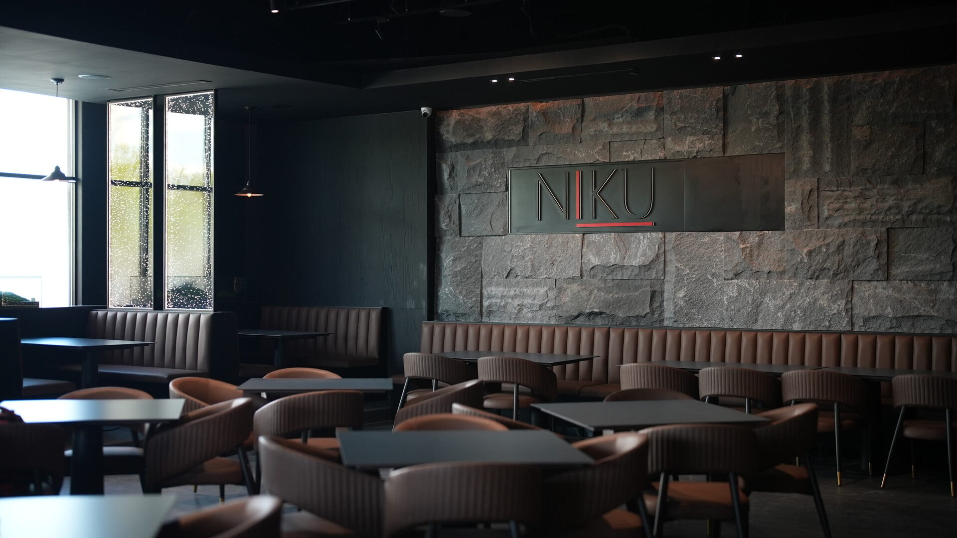 Stone walls, Edison lighting, and bubble glass partitions inside Niku Kitchen.Sushi.Bar